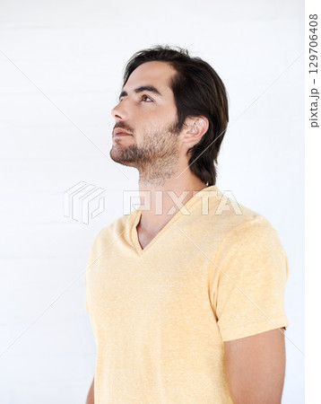 Casual, thinking and man looking up in a studio while being thoughtful or wondering for an idea. Pensive, daydreaming and young male model from Canada with stylish tshirt isolated by white background 129706408