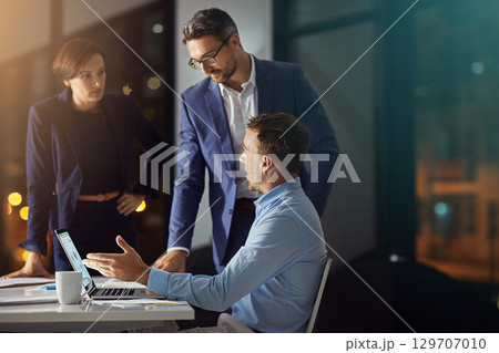 Business people, night office and planning on laptop with teamwork and collaboration working in dark. Digital marketing team of men and women together for innovation, ideas and talking about review 129707010