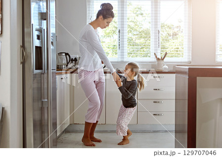 Kitchen dancing, mother and daughter in the morning at home with happiness dancing together. Mom, girl and parent care holding hands with a young kid in a house happy about family with a smile 129707046