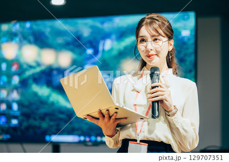 オフィスでマイクを持って話すビジネスウーマン 129707351