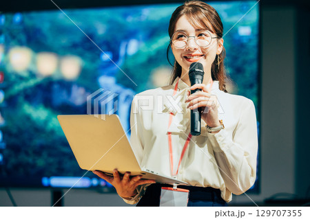 オフィスでマイクを持って話すビジネスウーマン 129707355