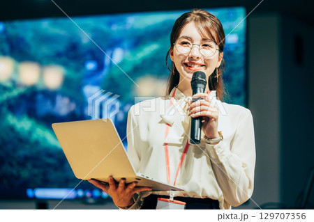 オフィスでマイクを持って話すビジネスウーマン 129707356
