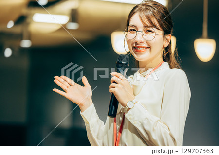 オフィスでマイクを持って話すビジネスウーマン オフィスでマイクを持って話すビジネスウーマン 129707363