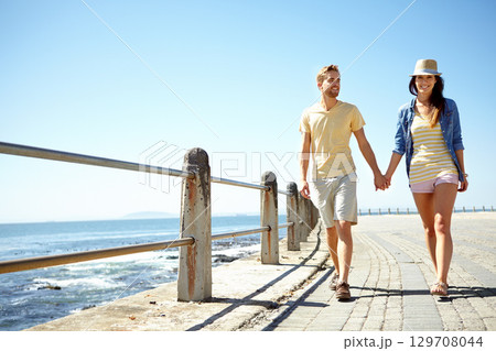 Beach, travel and happy couple holding hands while walking, talking and having fun on summer vacation. Sea, holiday and young man with woman bond, calm and happy, smile and relax together in Florida 129708044