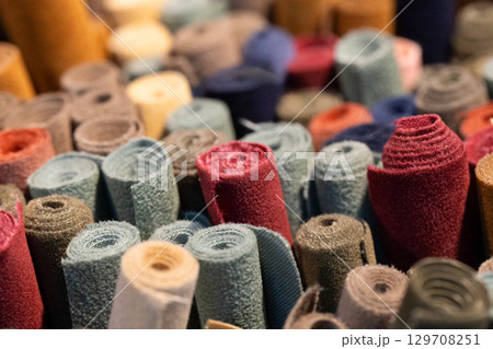 Colorful rolls of fabric stacked together in a vibrant display showcasing various textures and patterns 129708251