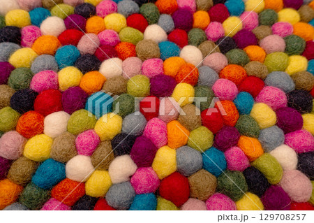 Colorful felt balls arranged in a vibrant pattern creating a lively textile surface design Colorful felt balls arranged in a vibrant pattern creating a lively textile surface design 129708257