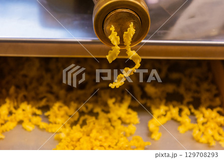 Freshly made pasta extruding from a machine onto a surface in a culinary setting Freshly made pasta extruding from a machine onto a surface in a culinary setting 129708293