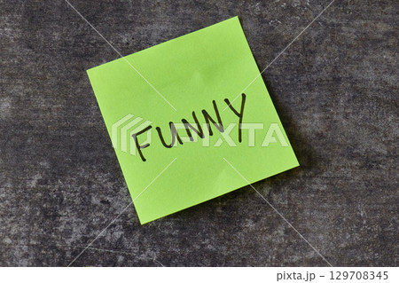 Note with the word funny written on a sticky note on a dark background 129708345