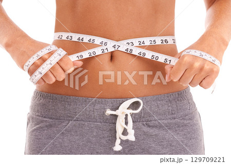 Fitness, health and woman with tape measure for stomach in studio isolated on a white background. Diet, wellness and slim female model measuring waist to track weightloss goals, progress or targets. Fitness, health and woman with tape measure for stomach in studio isolated on a white background. Diet, wellness and slim female model measuring waist to track weightloss goals, progress or targets. 129709221