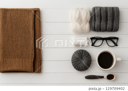 White table with a brown scarf, a white hat, a pair of glasses 129709402