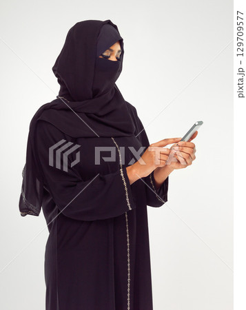 Muslim, phone and social media with an islamic woman in studio on a gray background for communication or networking. Contact, internet and islam with a female typing a text message or online post Muslim, phone and social media with an islamic woman in studio on a gray background for communication or networking. Contact, internet and islam with a female typing a text message or online post 129709577
