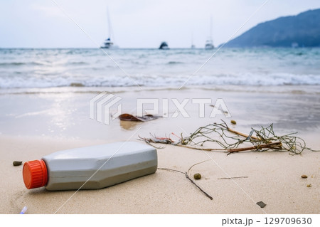 Bottle is laying on the beach, next to some seaweed. Green peace 129709630