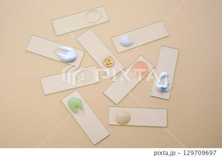 Textures of various cosmetic products on slides on a beige background. Textures of various cosmetic products on slides on a beige background. 129709697