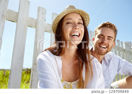 Portrait, love and date with a couple in the park during summer vacation or holiday together in nature. Spring, garden and relax with a man and woman sitting in a field for dating or bonding 129709849