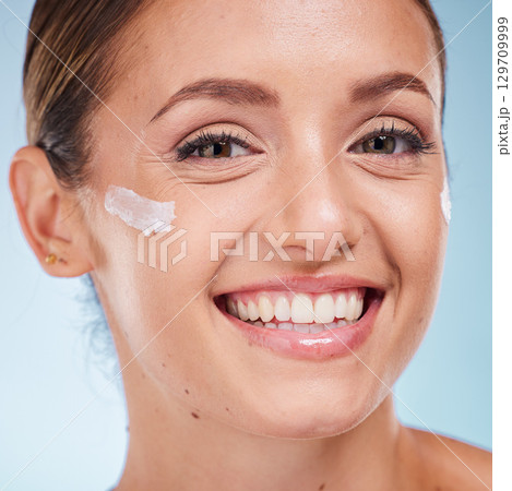 Skincare, beauty and portrait of a woman with face cream for health, wellness and natural face routine. Cosmetic, happy and model with facial lotion, spf or creme isolated by a blue studio background Skincare, beauty and portrait of a woman with face cream for health, wellness and natural face routine. Cosmetic, happy and model with facial lotion, spf or creme isolated by a blue studio background 129709999