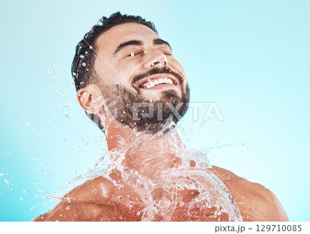 Water, splash and skincare with face of man for shower, self care and natural cosmetics. Luxury, hydration and refreshing with model for dermatology, wellness and cleaning in blue background studio Water, splash and skincare with face of man for shower, self care and natural cosmetics. Luxury, hydration and refreshing with model for dermatology, wellness and cleaning in blue background studio 129710085