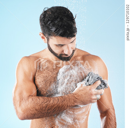 Washing body, skincare and man cleaning for hygiene, natural health and shower on a blue studio background. Morning routine, soap and healthy model showering to clean skin with a cloth and water Washing body, skincare and man cleaning for hygiene, natural health and shower on a blue studio background. Morning routine, soap and healthy model showering to clean skin with a cloth and water 129710102