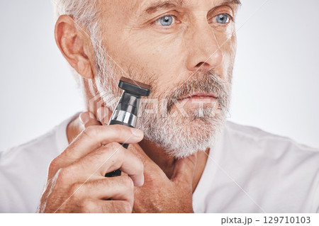 Senior man, shaving facial hair and grooming beard for skincare, hygiene and wellness with dermatolgy cosmetics. Hair removal, epilation and beauty of elderly male cleaning face on studio background 129710103