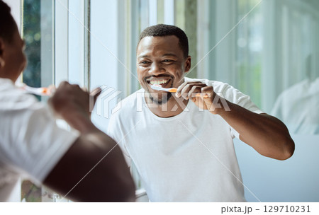 Morning, happy and black man brushing teeth in bathroom for health, hygiene and clean smile. Self care, cleaning and oral hygiene for healthy teeth of person smiling with confidence in home. Morning, happy and black man brushing teeth in bathroom for health, hygiene and clean smile. Self care, cleaning and oral hygiene for healthy teeth of person smiling with confidence in home. 129710231