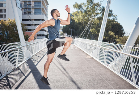 Fitness, running and exercise with a sports man on a bridge in the city for a cardio or endurance workout. Health, runner and training with a male athete exercising in an urban town for wellness 129710255