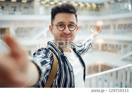Library, student selfie and man in university, college or school. Education scholarship, learning and face portrait of young male taking a photo or picture for memory, social media or online profile. Library, student selfie and man in university, college or school. Education scholarship, learning and face portrait of young male taking a photo or picture for memory, social media or online profile. 129710313