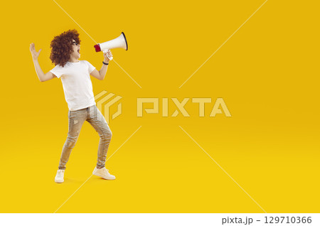 Happy preteen boy shouting into megaphone making announcement. 129710366