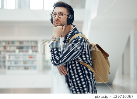 Thinking, headphones and library student at university, college or academy idea for research, learning and knowledge. Study, education and creative, geek man listening to audio for school inspiration 129710367