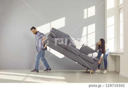 Happy young couple carrying sofa to their new home Happy young couple carrying sofa to their new home 129710392