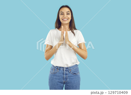 Portrait of happy, pretty, smiling, young woman in white T-shirt and blue jeans on an isolated blue background. 129710409