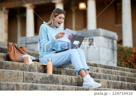 Wow, success or happy student with news, results or report feedback at university or college campus steps. Laptop, education or excited school girl reading exam paper marks or test score with pride 129710410