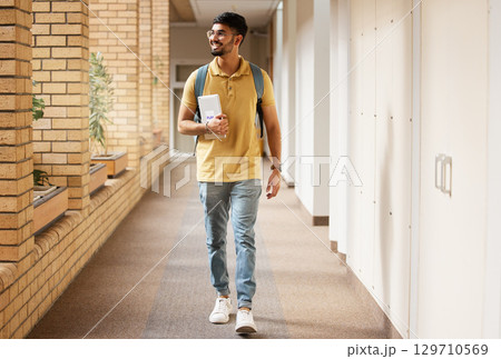 University student, college and indian man walking with a smile and backpack down campus corridor. Gen z male happy about education, learning and future after studying with scholarship at school 129710569