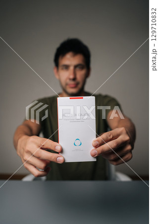 Ufa, Russia - 21 July 2025. Vertical portrait of blogger male holding and presenting new IQOC 3 duos tobacco heating system, innovative electronic cigarette for modern smokers seeking harm reduction Ufa, Russia - 21 July 2025. Vertical portrait of blogger male holding and presenting new IQOC 3 duos tobacco heating system, innovative electronic cigarette for modern smokers seeking harm reduction 129710832