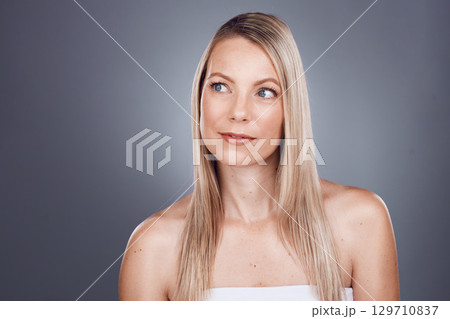 Hair, beauty and thinking with a model woman in studio on a gray background for a haircare treatment idea. Wellness, health and keratin with an attractive young female posing to promote natural care 129710837
