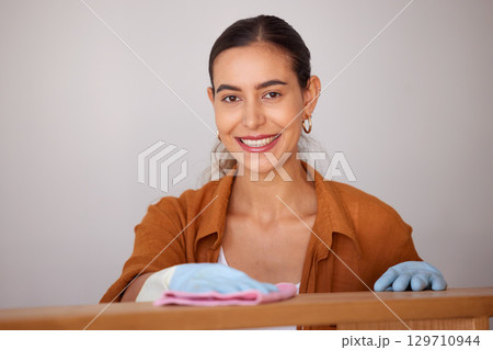 Portrait, cleaning and wipe with a woman housekeeper or cleaner using a rag cloth to dust furniture. Face, bacteria and dirt with a female working to service a dirty apartment for housekeeping 129710944