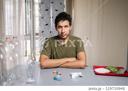 Portrait of confident biologist sitting at table, crossing arms while mixing fertilizer from recycled bottles for innovative vertical garden setup, emphasizing eco-friendly urban agriculture 129710948