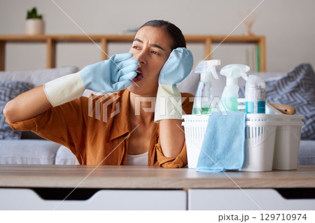 Cleaning, yawn and tired with a woman housekeeper yawning while working in a home as a cleaner. Clean, bored and hygiene with a female suffering burnout from housekeeping as a maid with disinfectant 129710974