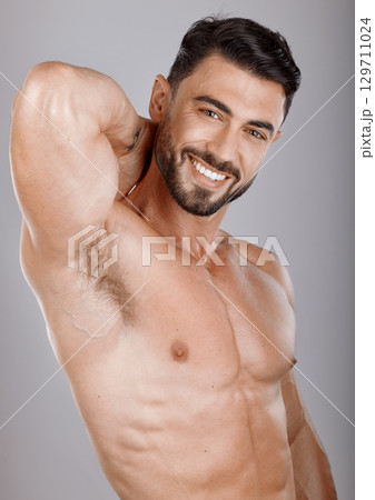 Portrait, beauty and body with a man bodybuilder in studio on a gray background for health or fitness. Face, training and exercise with a handsome model male posing to promote a healthy lifestyle 129711024