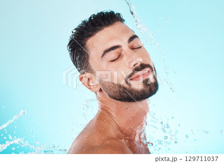 Water, splash and skincare with face of man for shower, self care and natural cosmetics. Luxury, hydration and refreshing with model for dermatology, wellness and cleaning on blue background studio Water, splash and skincare with face of man for shower, self care and natural cosmetics. Luxury, hydration and refreshing with model for dermatology, wellness and cleaning on blue background studio 129711037
