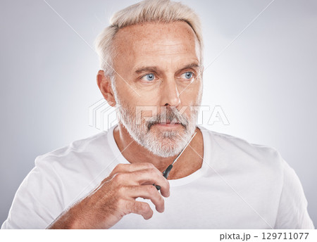 Scissors, wellness and man cutting beard on face for morning routine, grooming and cosmetic hygiene on a studio background. Barber, skincare and senior model trimming facial hair for clean beauty 129711077