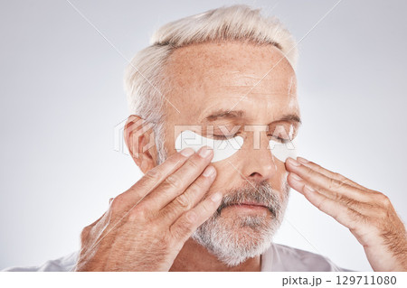 Eyes patch, senior man and skincare face in studio for self care dermatology, facial and cosmetics advertising in morning. Model with hands application of collagen mask or anti aging beauty product Eyes patch, senior man and skincare face in studio for self care dermatology, facial and cosmetics advertising in morning. Model with hands application of collagen mask or anti aging beauty product 129711080