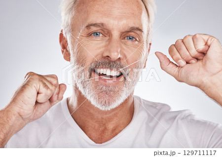 Face, dental floss and senior man in studio isolated on a gray background. Portrait, cleaning and elderly male model with product flossing teeth for oral wellness, tooth care and healthy gum hygiene 129711117