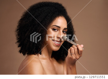 Black woman, studio portrait and brush for foundation, beauty or cosmetic self care by backdrop with smile. Model, happy and powder makeup for face, skincare glow or application by studio background 129711551