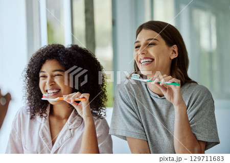 Oral care, toothbrush and female friends with a hygiene, health and wellness morning routine. Happy, smile and interracial women doing a dental treatment while brushing teeth in the bathroom. 129711683
