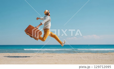 A joyful man in a hat and sunglasses leaps enthusiastically on a sandy beach, holding a vintage suitcase, with the blue sea and sky in background. Captures the essence of vacation, freedom, happiness 129712095