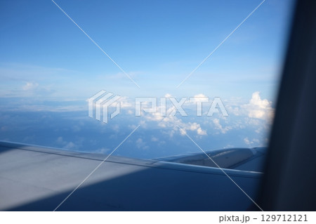 Serene Aerial View of Fluffy Clouds from Airplane Window Focus on Background Serene Aerial View of Fluffy Clouds from Airplane Window Focus on Background 129712121