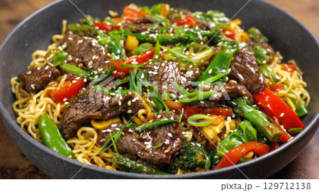 A vibrant and appetizing close-up of a beef and broccoli stir-fry with noodles, garnished with sesame seeds and green onions. Ideal for food blogs, menus, healthy eating campaigns, culinary promotions 129712138