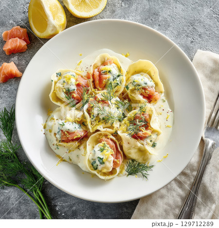 Fresh Tuscan tortelli pasta filled with a delightful combination of creamy ricotta and smoky salmon, served in a rich lemon-dill cream sauce 129712289