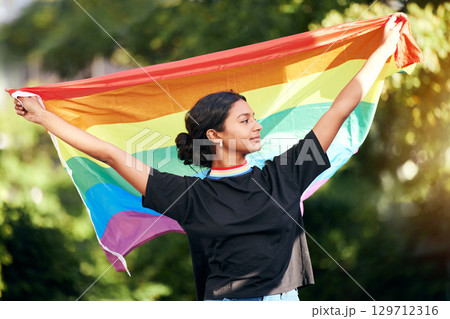 Rainbow, flag and human rights with an indian woman in celebration of lgbt gay pride alone outdoor. Freedom, equality and lgbtq with a happy female outside celebrating her equality or inclusion 129712316