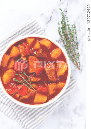 meat goulash with potatoes and carrots, sweet peppers, in a saucepan, top view, traditional Hungarian soup, homemade, no people, 129712490
