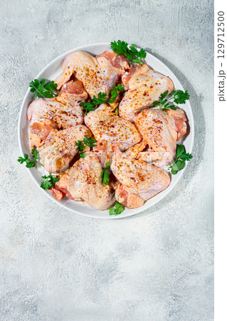 Marinated chicken wings prepared for grilling with spices and fresh herbs ready for cooking 129712500